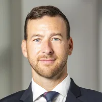 person with short brown hair in a suit