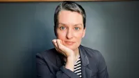 headshot of a person with short hair resting their chin on their hand