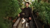 Person sitting on stool surrounded by plants